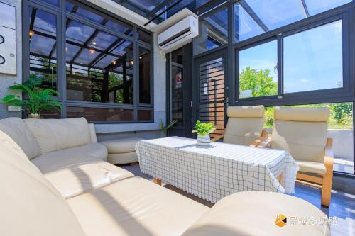a conservatory with white furniture and large windows at Harbour Enjoy Homestay in Yilan City
