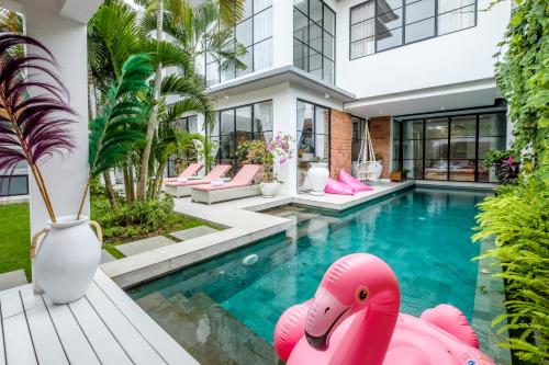 ein Haus mit einem Pool mit rosa aufblasbaren Flamingos in der Unterkunft Maison Jolie Villa by Hombali in Canggu