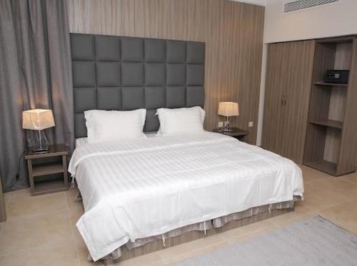 a bedroom with a large white bed with two lamps at Al Raha Apartment Hotel in Jeddah