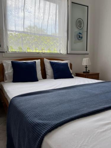 Elle comprend un grand lit avec des oreillers bleus et une fenêtre. dans l'établissement G&S Beach House, à Flogita