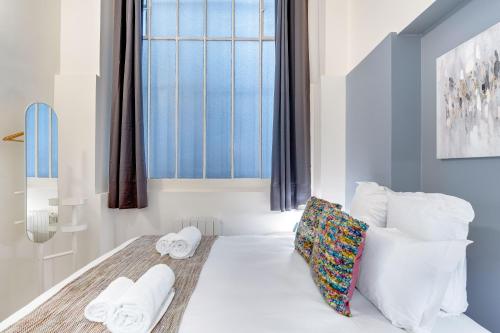 une chambre avec un lit avec des oreillers blancs et une fenêtre dans l'établissement Sweett - Rue de Lallier, à Paris
