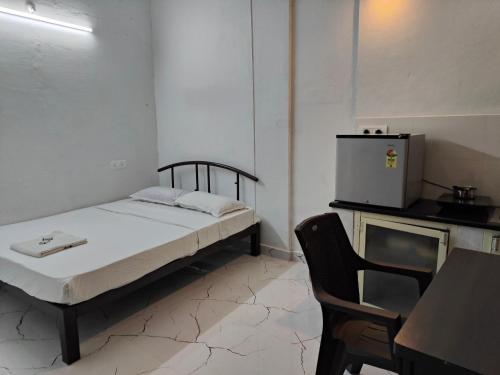 małą sypialnię z łóżkiem i małą lodówką w obiekcie Mysore Studio Rooms w mieście Mysuru