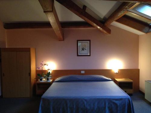 a bedroom with a bed with blue sheets and two lights at Hotel Villa Reale in Argenta