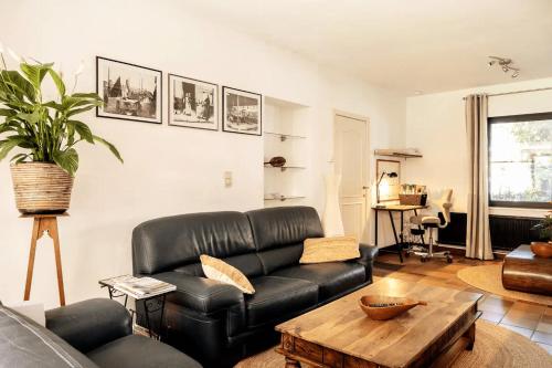 a living room with a black leather couch and a table at Holiday home Keysersnest in Gistel