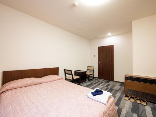 Schlafzimmer mit einem Bett, einem Tisch und Stühlen in der Unterkunft Tabist Ooriya Kochi in Sagamichō