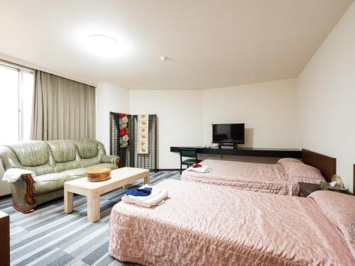 Habitación de hotel con 2 camas y sofá en Tabist Ooriya Kochi, en Sagamichō