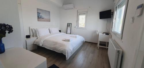 ein weißes Schlafzimmer mit einem Bett und einem TV in der Unterkunft ALBA OCEAN VIEW LUXURY RESIDENCE in Nea Anchialos