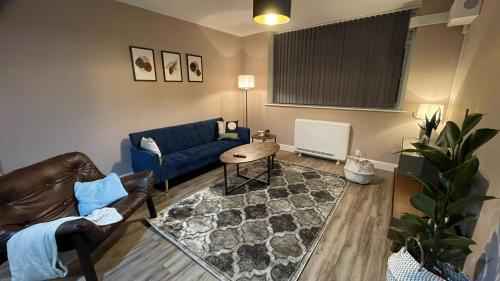 a living room with a blue couch and a table at Lovely 2 Bedroom Serviced Apartment with Parking in West Bromwich