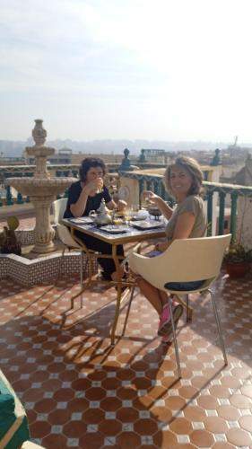 two women sitting at a table on a balcony at Riad Malak in Meknès