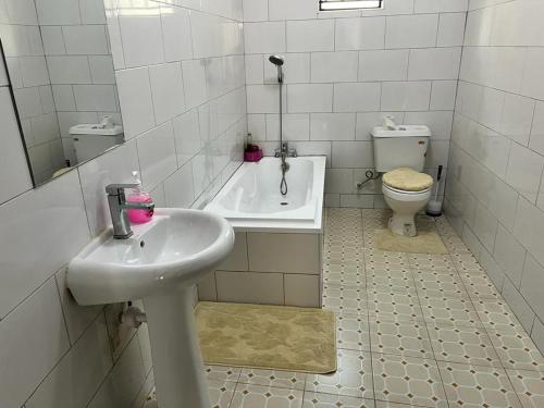 La salle de bains blanche est pourvue d'un lavabo et de toilettes. dans l'établissement Spacious and comfortable House in Kampala Uganda, à Kasiyirize