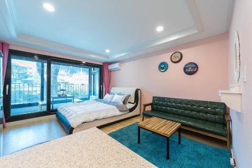 un soggiorno con divano verde e letto di Gangneung Haesolnaeeum Pension a Gangneung