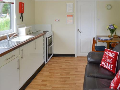 a kitchen with a sink and a couch in a room at Maud - Uk12693 in Stalham