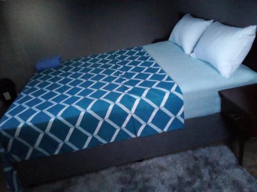 a bed with blue and white sheets and pillows at Waltershort Guest House and Bed and Breakfast in Pietermaritzburg