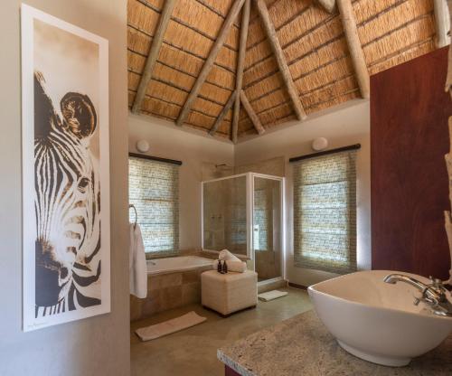uma casa de banho com banheira e uma imagem de zebra na parede em Xanatseni Private Camp em Klaserie Private Nature Reserve