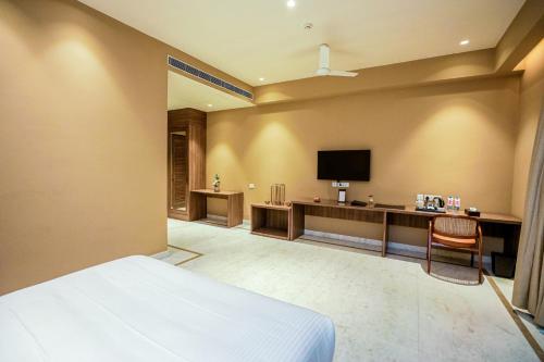 a hotel room with a bed and a television at Gulab Kothi by Royal Orchid Hotels Limited Varanasi in Varanasi