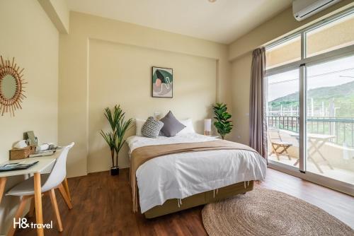 1 dormitorio con cama, escritorio y balcón en H& Yu Krung Style Inn en Taitung