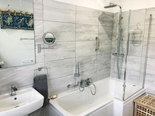 a bathroom with a shower and a tub and a sink at May Escape in Heswall