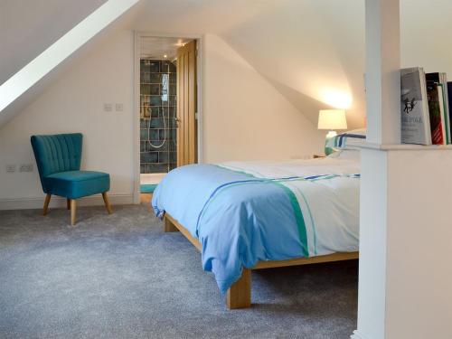 a bedroom with a bed and a blue chair at The Hen House At The Old Parsonage in Cote Brook