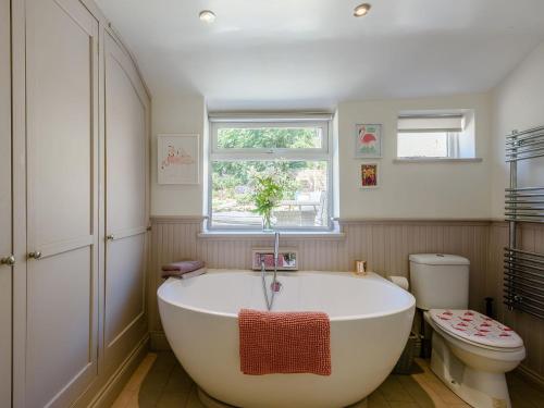 a bathroom with a large tub and a toilet at Rose Cottage in Reedham