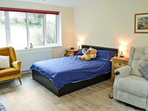 un osito de peluche sentado en una cama en un dormitorio en Burnside, en Torthorwald