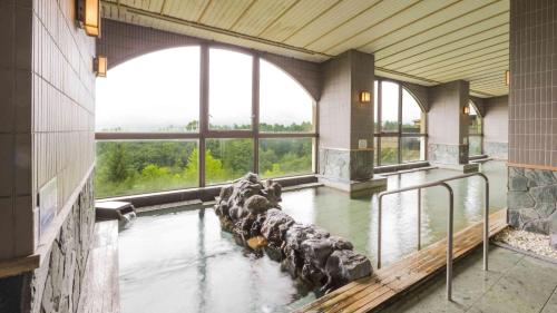a large pool of water in a building with windows at Hotel Morinokaze Oshuku in Shizukuishi