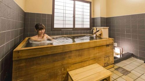 una donna in una grande vasca da bagno in legno di Hotel Morinokaze Oshuku a Shizukuishi