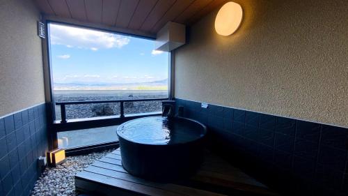 a bathroom with a tub with a large window at Hotel Morinokaze Oshuku in Shizukuishi
