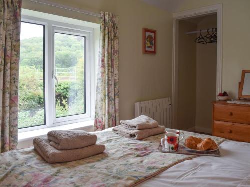 a bed with a tray of bread and a window at Cobbs Cottage in Grosmont
