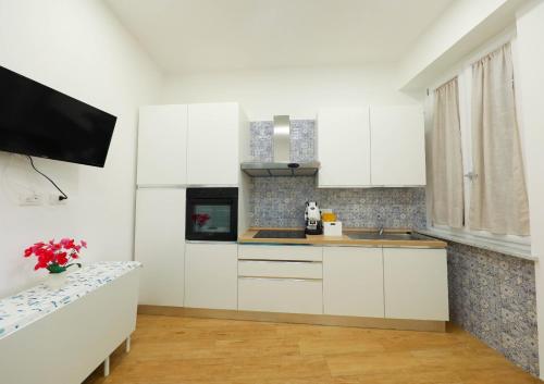 a kitchen with white cabinets and a tv in it at Vient' e mar suite in Castellammare di Stabia