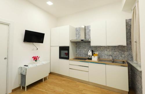 a kitchen with white cabinets and a tv on the wall at Vient' e mar suite in Castellammare di Stabia