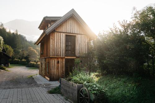 a small wooden house with a wheel in front of it at Chalet am Sonnenhang in Obertraun