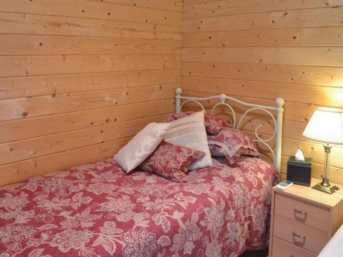 - une chambre avec un lit et un mur en bois dans l'établissement Gooseberry Lodge, à Tollard Royal
