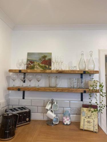 una cucina con ripiani in legno riempiti con bicchieri da vino di Stunning Apartment in Newburgh Scotland sleeps 4 a Cupar