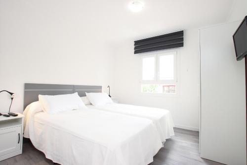 a white bedroom with a white bed and a window at Apt RIERES in Port de Pollensa