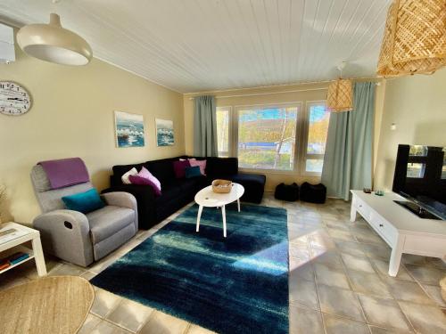 een woonkamer met een bank en een tafel bij Villa Arktika porealtaallinen mökki Nuorgamissa Tenojoen ja tunturien vieressä in Nuorgam