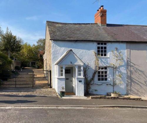 a white house with a white door on a street at Cosy two bedrooom cottage set in a Dorset village in Sturminster Newton
