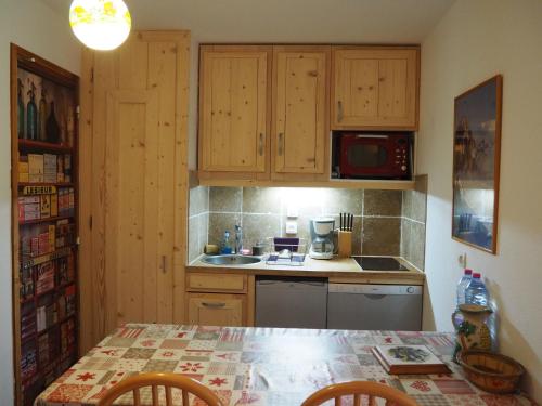 une cuisine avec des armoires en bois et une table avec des chaises dans l'établissement travelski home classic - Résidence Les Balcons d'Olympie, aux Menuires