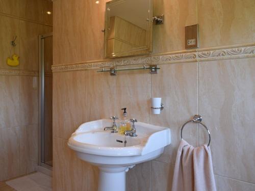 een badkamer met een witte wastafel en een spiegel bij Lawford Lodge in Bonnybridge
