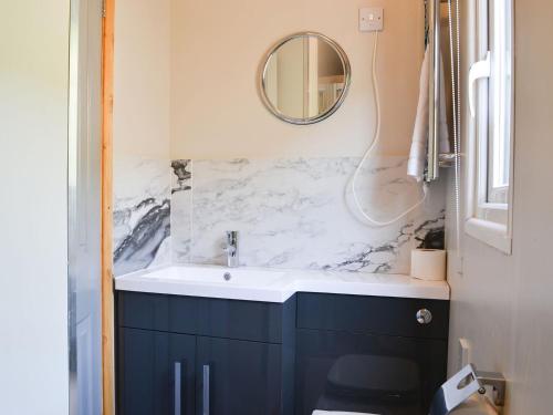 uma casa de banho com um lavatório e um espelho em The Rocking Lodge em Threlkeld