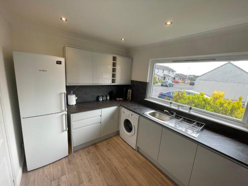 a kitchen with a white refrigerator and a window at Casa Fresa - Kintail House in Broughty Ferry