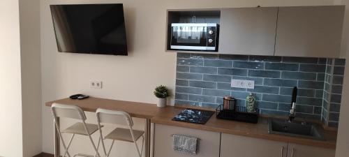 a kitchen with a counter with chairs and a microwave at Panoráma Apartman Mogyoród in Mogyoród