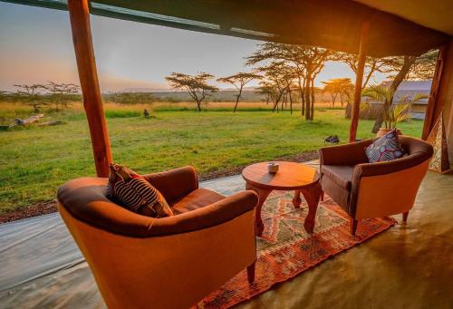 a living room with two chairs and a table in front of a field at Kandili Camp in Musiara Campsite