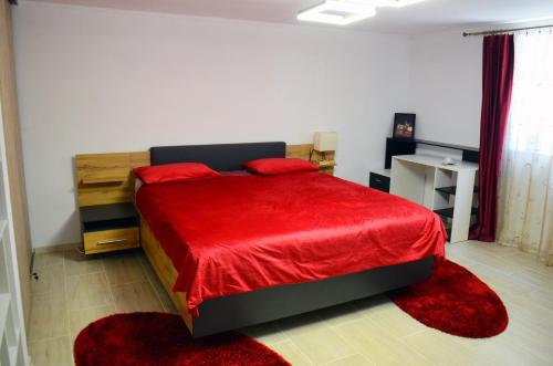 a bedroom with a red bed with red sheets and red rugs at Lovely 2 bedroom apartment in the City Centre of Oradea in Oradea