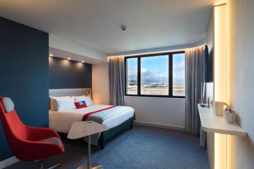 a hotel room with a bed and a red chair at Holiday Inn Express - Paris - CDG Airport, an IHG Hotel in Roissy-en-France