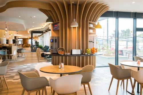 a lobby of a restaurant with tables and chairs at Holiday Inn Express - Paris - CDG Airport, an IHG Hotel in Roissy-en-France