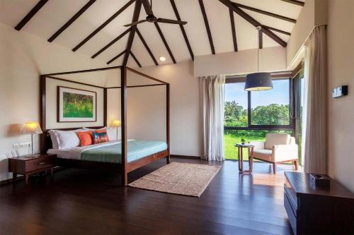 a bedroom with a canopy bed and a living room at StayVista at Bella Aries in Calangute