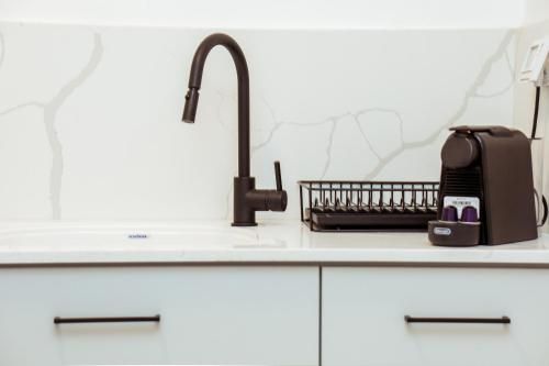 um balcão de cozinha com um lavatório e uma torneira preta em הרצל בוטיק מבית דומוס - Herzl Boutique Apartments by Domus em Beer Sheva