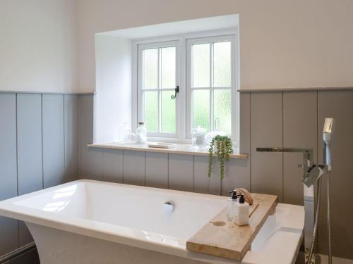 a bath tub in a bathroom with a window at Grace Cottage in Umberleigh Bridge