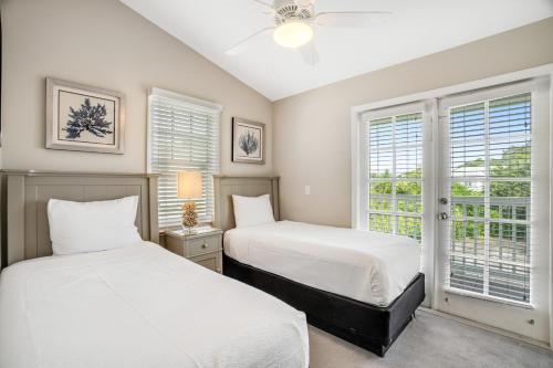 two beds in a room with two windows at Key Lime Villa in Duck Key