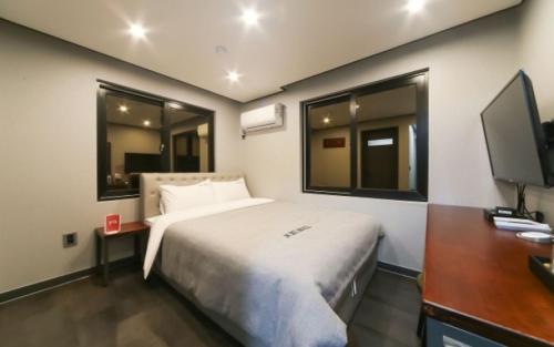 Schlafzimmer mit einem Bett, einem Schreibtisch und einem TV in der Unterkunft Tongyeong Mu in Tongyeong